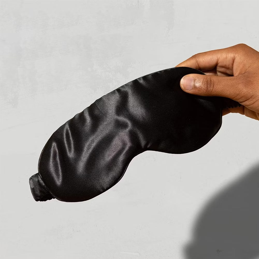 mano che tiene una mascherina da notte in seta nera